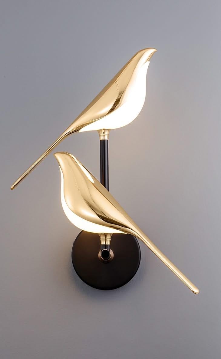 Gold bird-shaped wall light fixture on a gray background