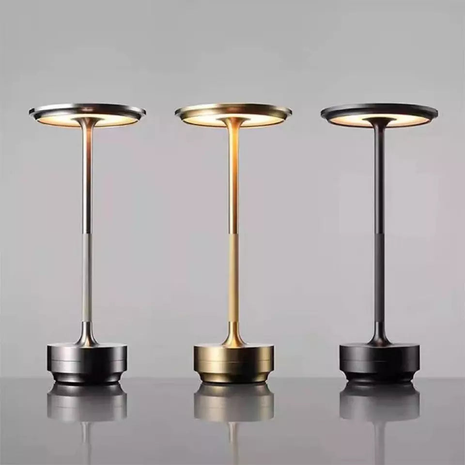 Three portable lamps with different finishes on a reflective surface and gray background