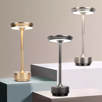 Three modern table lamps in gold, silver, and black on a geometric surface with a neutral background.