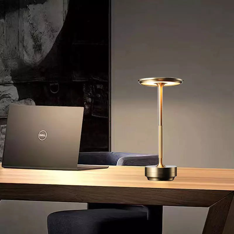 Gold desk lamp and Dell laptop on a wooden desk with a dark background