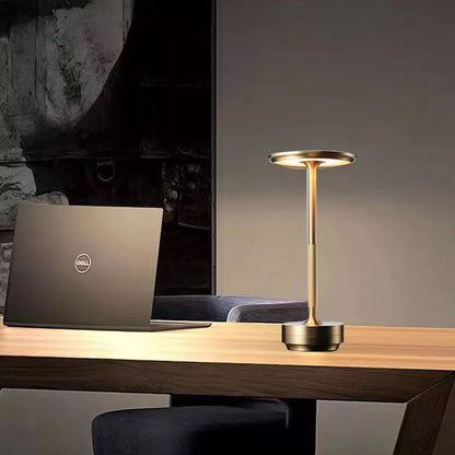 Gold desk lamp and Dell laptop on a wooden desk with a dark background
