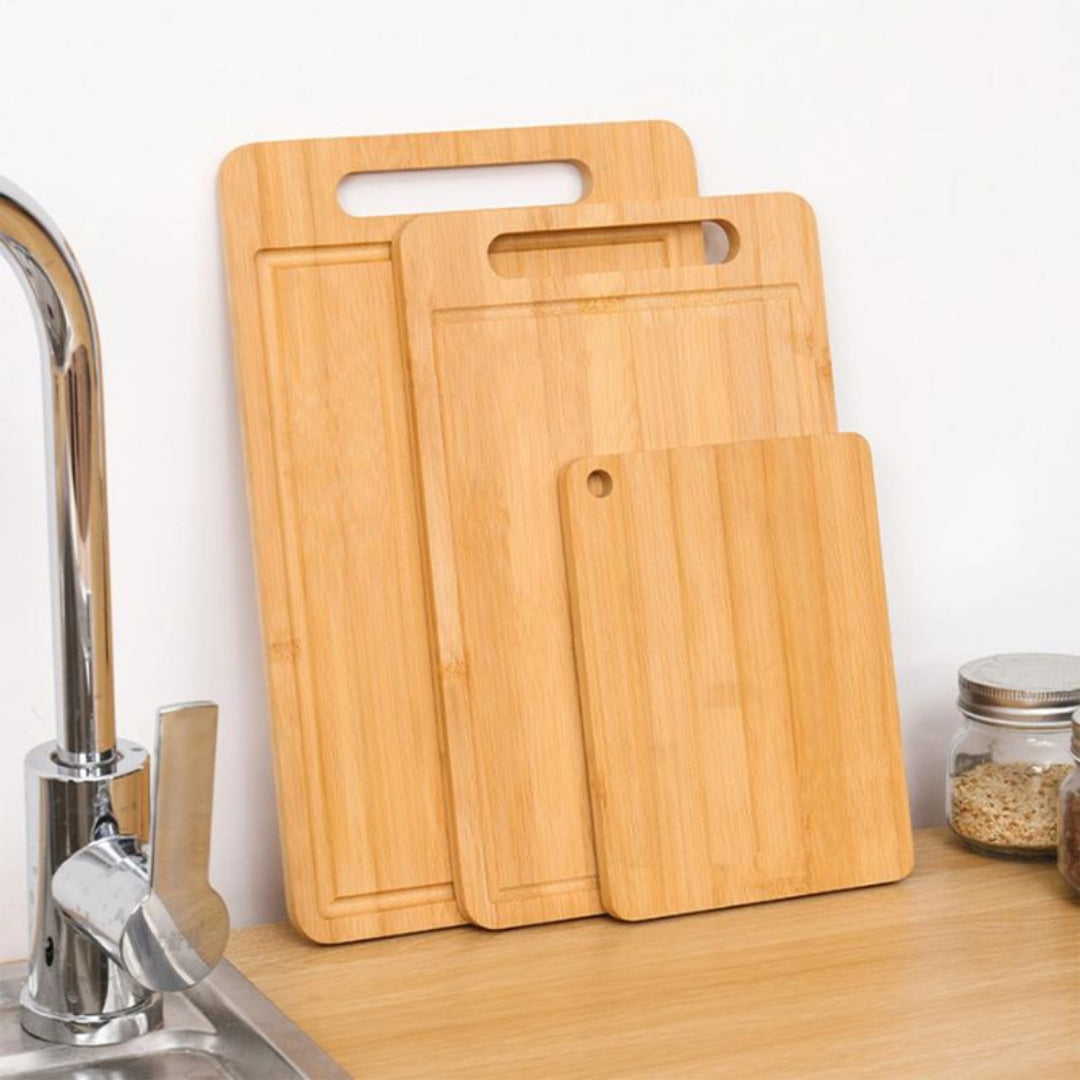 Set of wooden cutting boards on a kitchen counter with a sink in the background.