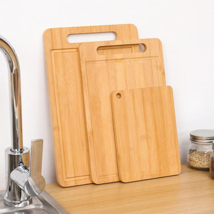 Set of wooden cutting boards on a kitchen counter with a sink in the background.