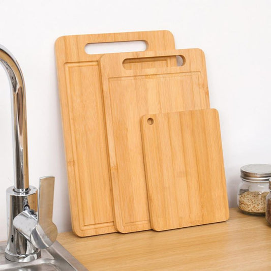 Set of wooden cutting boards on a kitchen counter with a sink in the background.