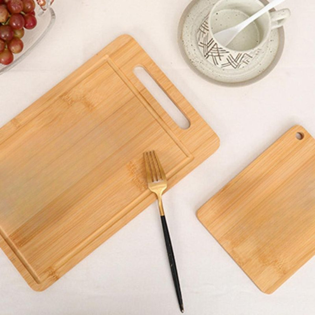 Two wooden cutting boards on a light surface with a fork and grapes.