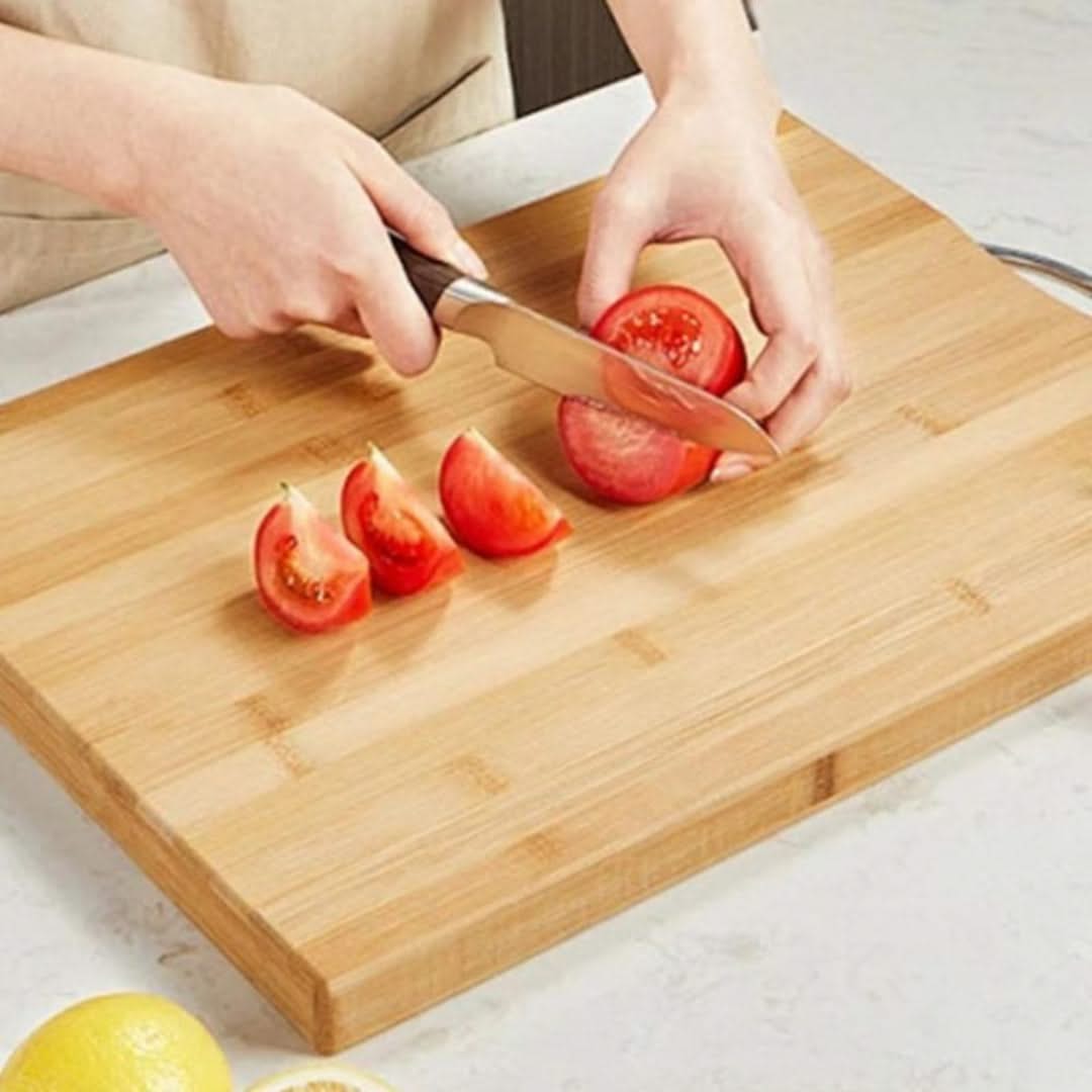 Person slicing tomatoes on a wooden cutting board with a knife.