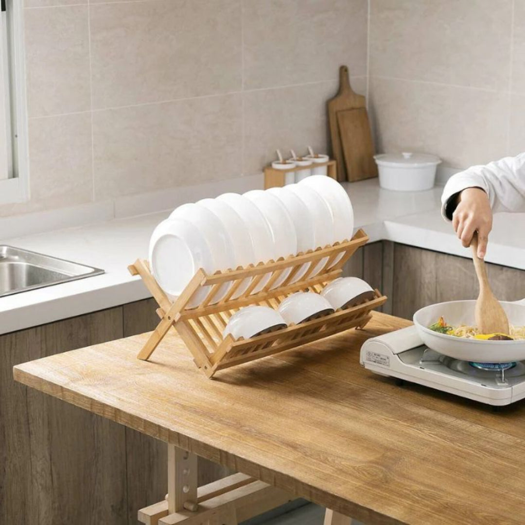 Wooden dish rack with white dishes on a kitchen counter.