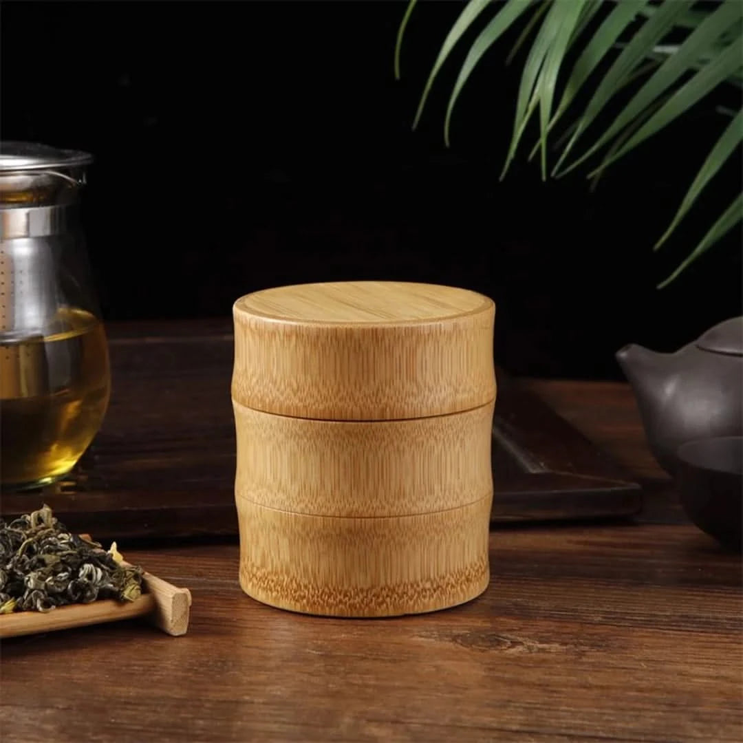 Josh & Tate - Bamboo Food Storage Container - Wooden tea canister on a wooden surface with tea leaves and a teapot in the background.
