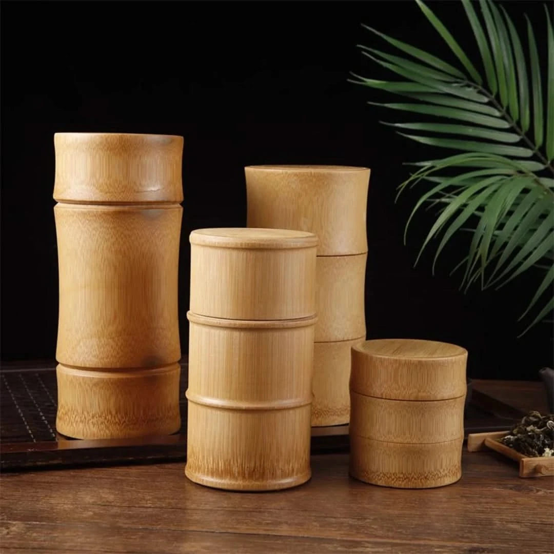 Josh & Tate - Bamboo Food Storage Container - Set of wooden containers on a wooden surface with a dark background and green leaves.