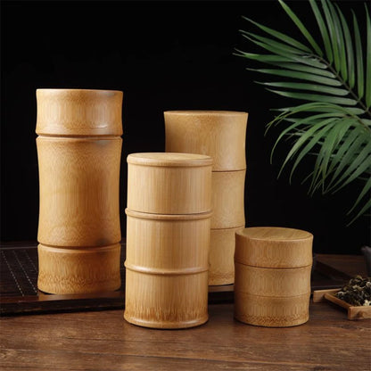 Josh & Tate - Bamboo Food Storage Container - Set of wooden containers on a wooden surface with a dark background and green leaves.