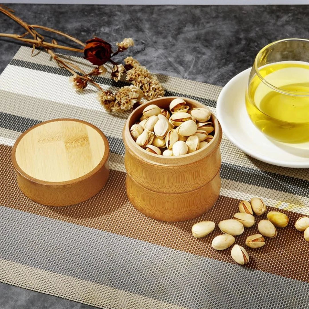 Josh & Tate - Bamboo Food Storage Container - Bamboo container with pistachios on a table with a glass of tea and flowers.