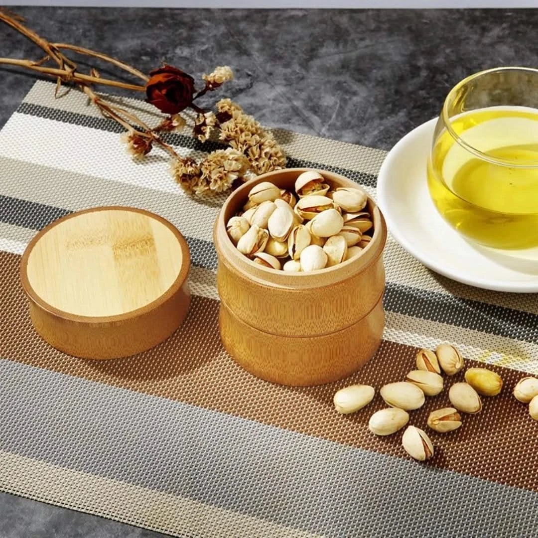 Josh & Tate - Bamboo Food Storage Container - Bamboo container with pistachios on a table with a glass of tea and flowers.