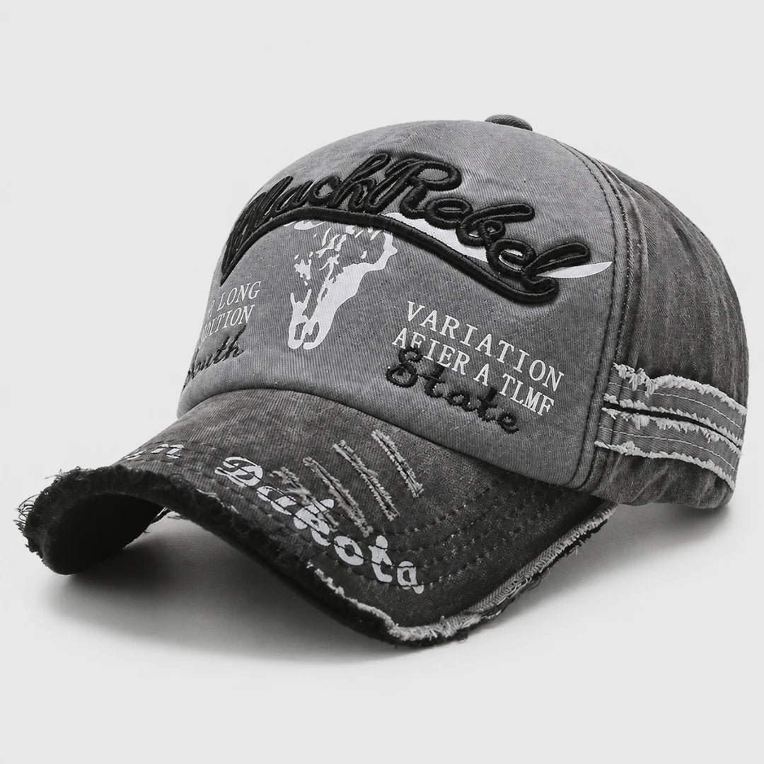 Josh & Tate - BlackRebel™ Distressed Cap - A distressed gray baseball cap with black and white graphic text and embroidery, including 'RustRock' and 'Vartation After A TMR Skate'.