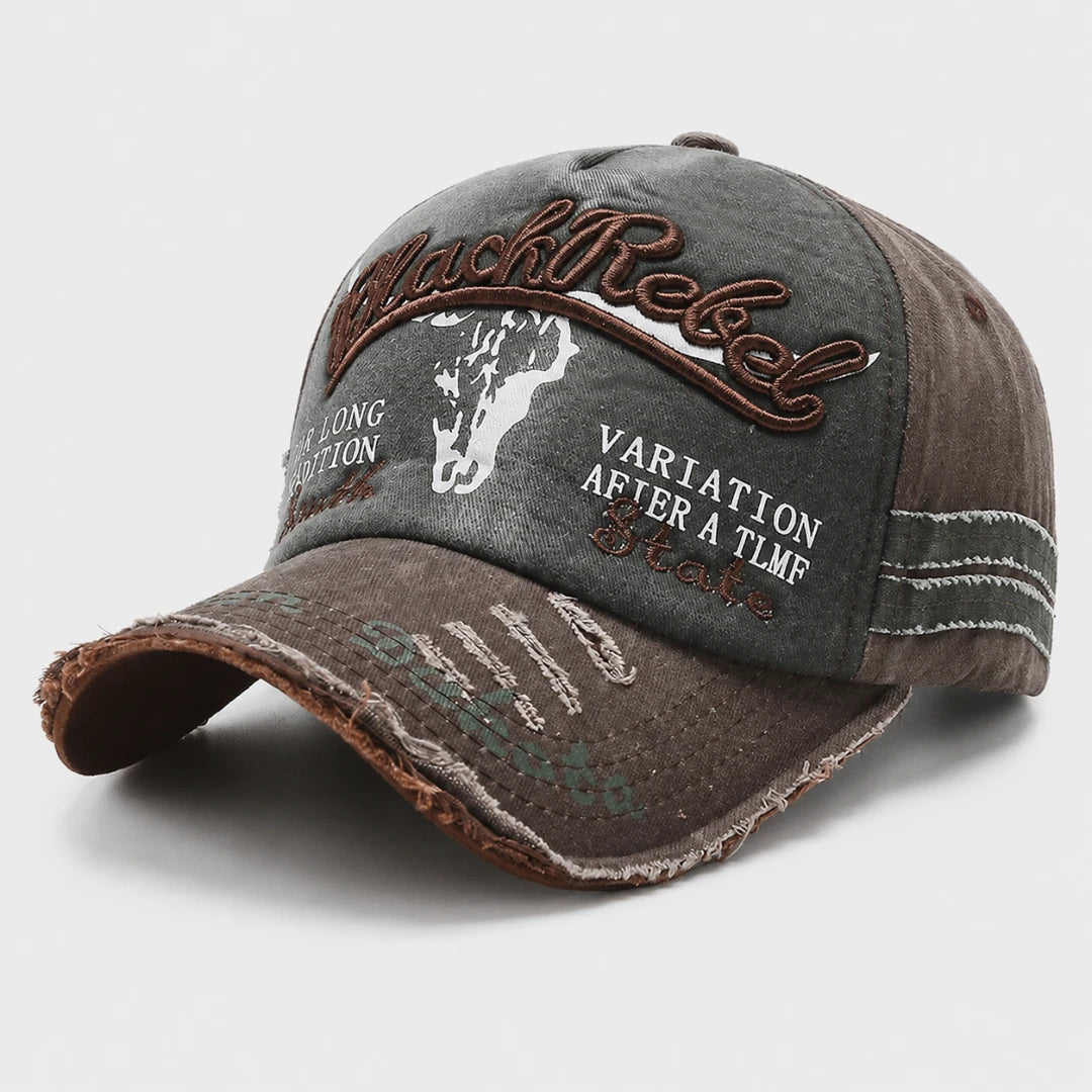Josh & Tate - BlackRebel™ Distressed Cap - A distressed baseball cap in washed charcoal gray and brown, featuring embroidered 'Black Rebel' text, a white steer illustration, and white slogan embroidery on the front panels.