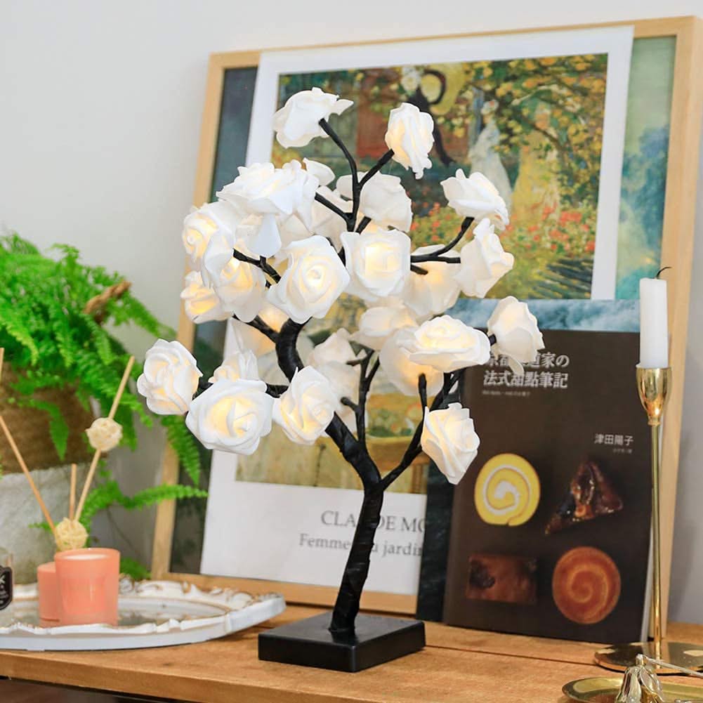 Decorative white flower lamp on a table with a book and candle in the background