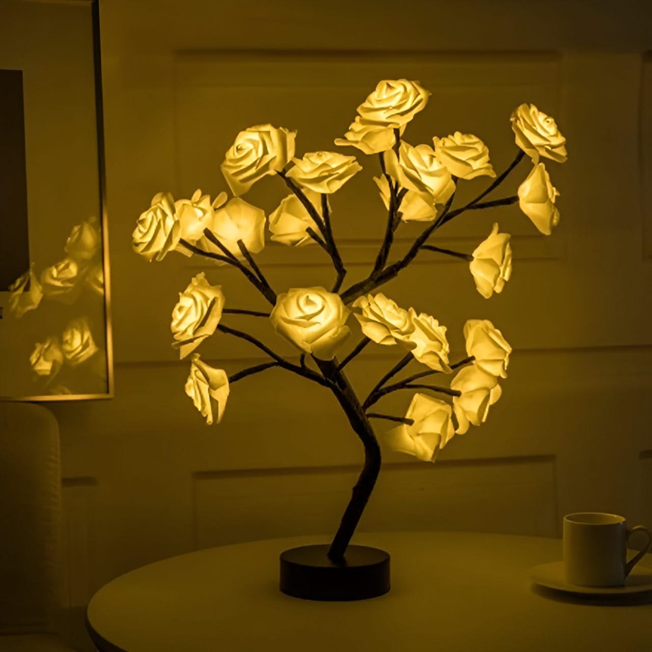 Decorative LED lamp shaped like a rose bush on a table with a cup in the background.