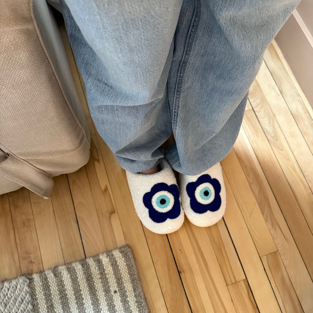 Person wearing blue jeans and white socks with blue flower designs on a wooden floor.