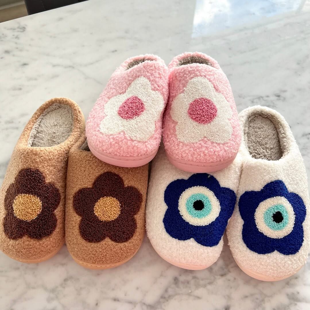 Pair of children's slippers with floral designs on a marble surface