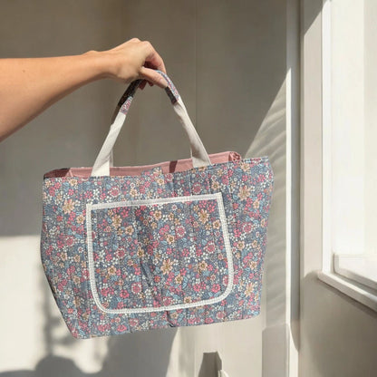 Josh & Tate - Blossom Tote Bag - Person holding a floral-patterned tote bag in a bright room with sunlight streaming in.