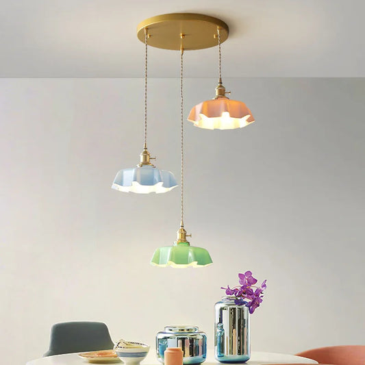 Three pendant lights hanging from a ceiling with a vase of flowers on a table below.