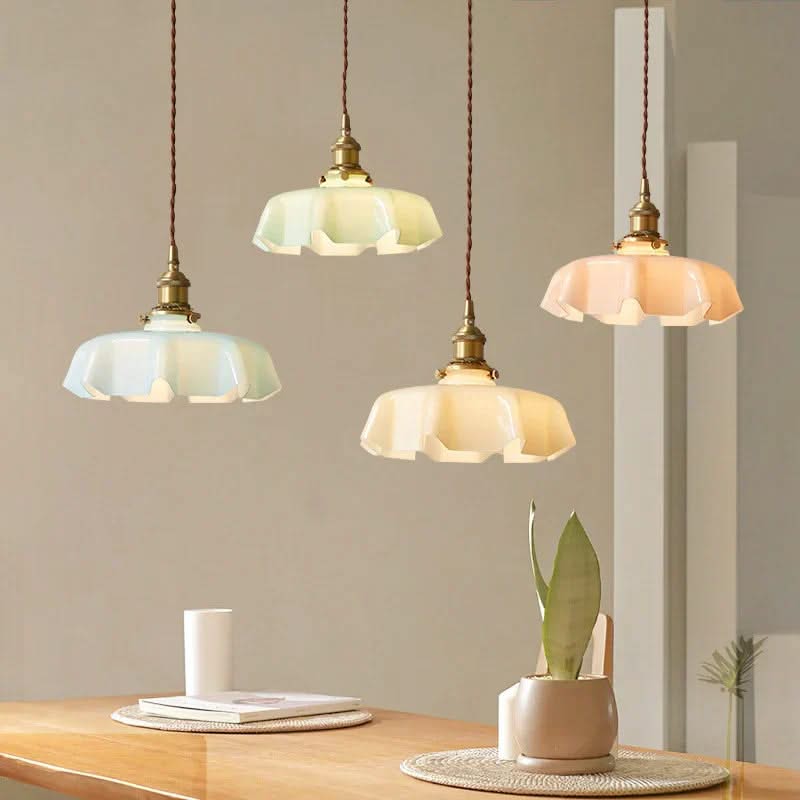 Three pendant lights hanging above a table with a plant and books in the background.