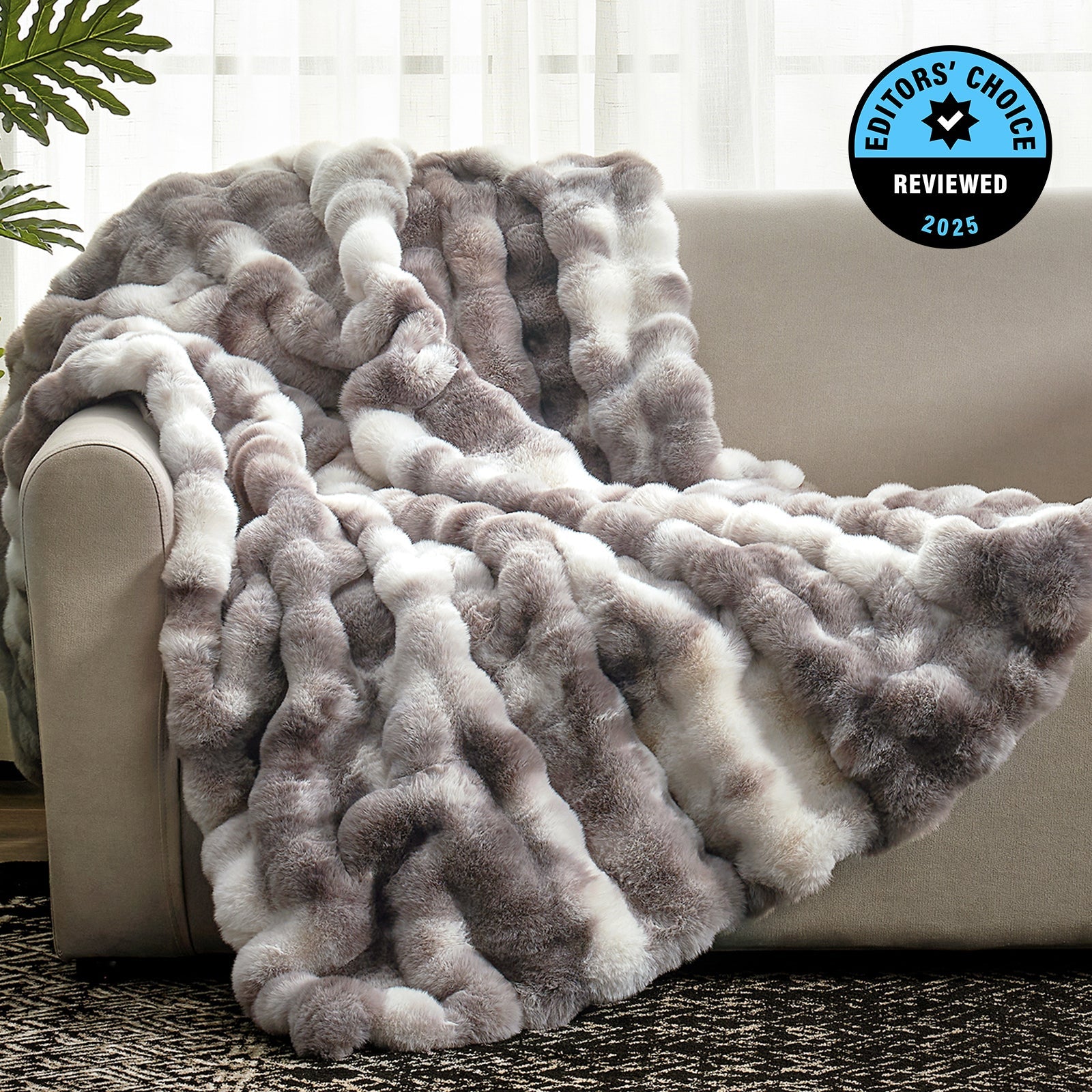 Gray and white fuzzy blanket draped over a beige couch with 'Editors' Choice' badge.