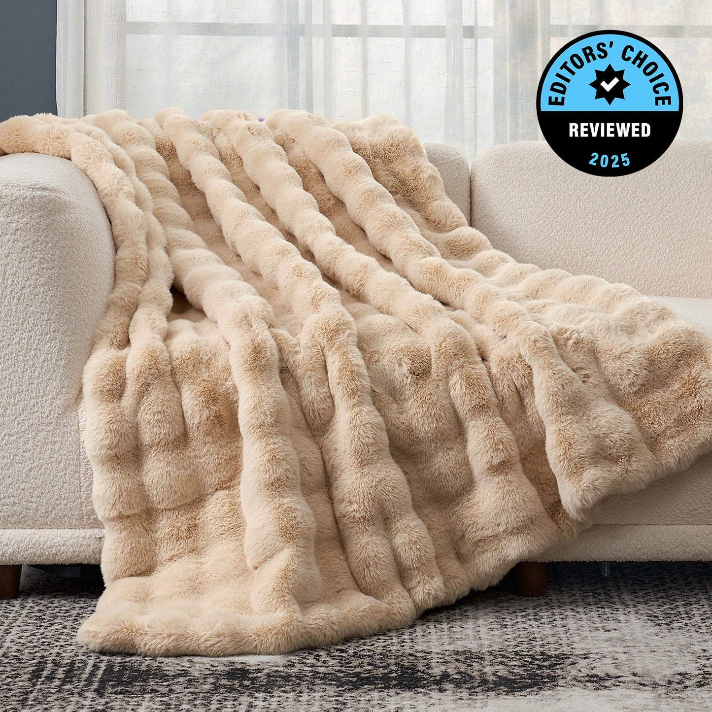 Beige fluffy blanket draped over a sofa with 'Editors' Choice' badge in the corner.
