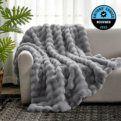 Gray textured blanket draped over a sofa with a plant and rug in the background, featuring an 'Editors' Choice' badge.
