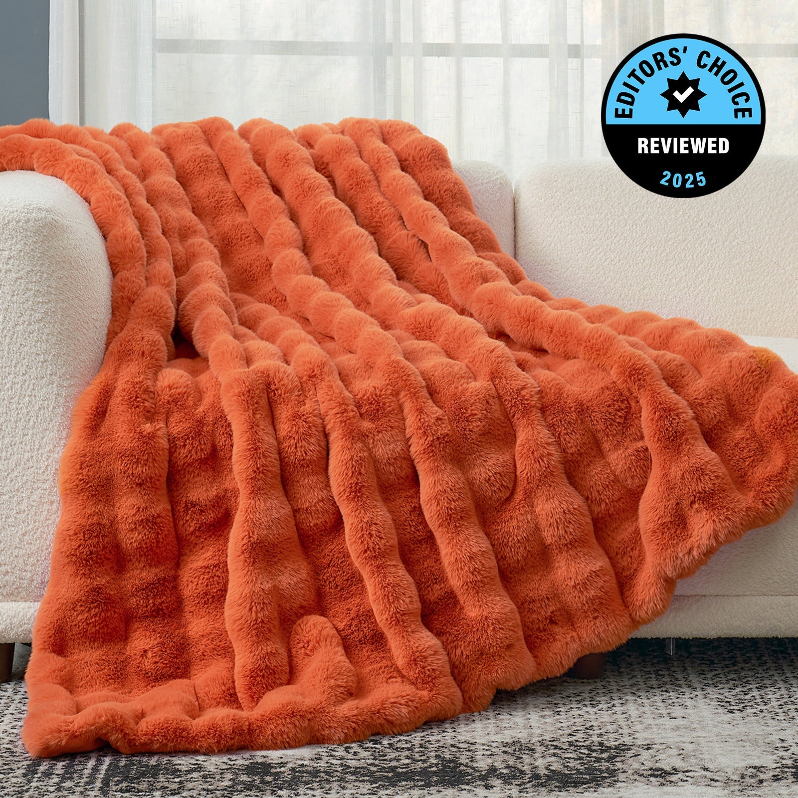 Orange textured blanket draped over a white couch with 'Editors' Choice' badge.