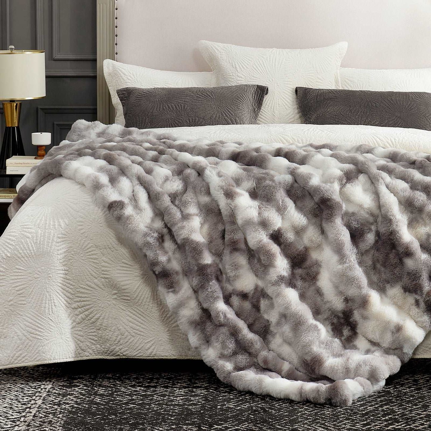 Gray textured blanket on a bed with white bedding and pillows in a bedroom setting.