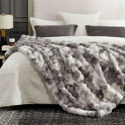 Gray textured blanket on a bed with white bedding and pillows in a bedroom setting.