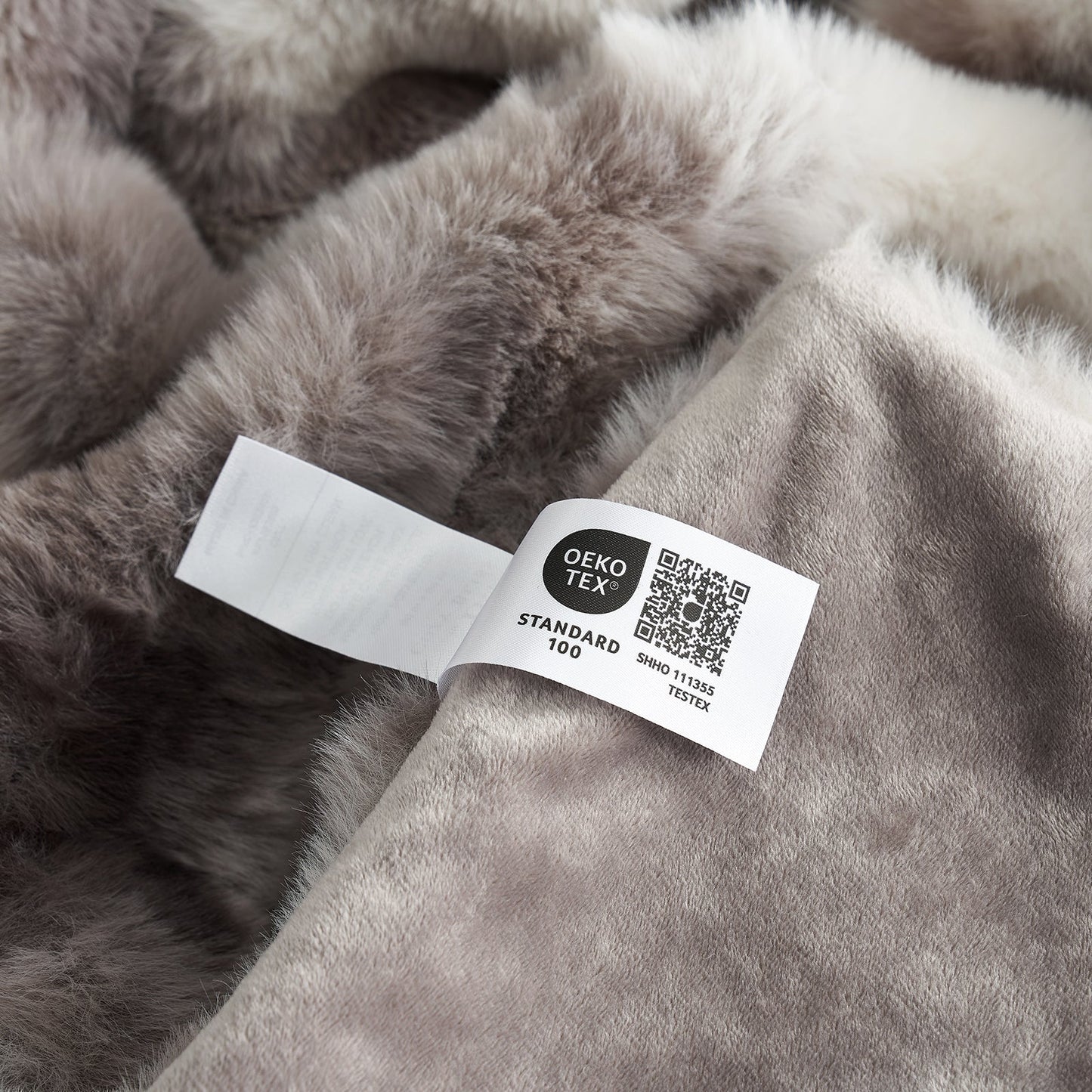 Gray fur fabric with an OEKO-TEX label on a close-up view