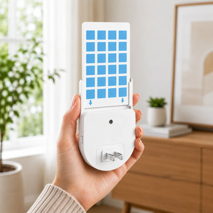 Josh & Tate - BugSheet™ Sticky Mosquito Catcher - A hand holds a white electronic device with a blue grid-patterned cover in a bright, modern room with a window, plant, and wooden cabinet in the background.