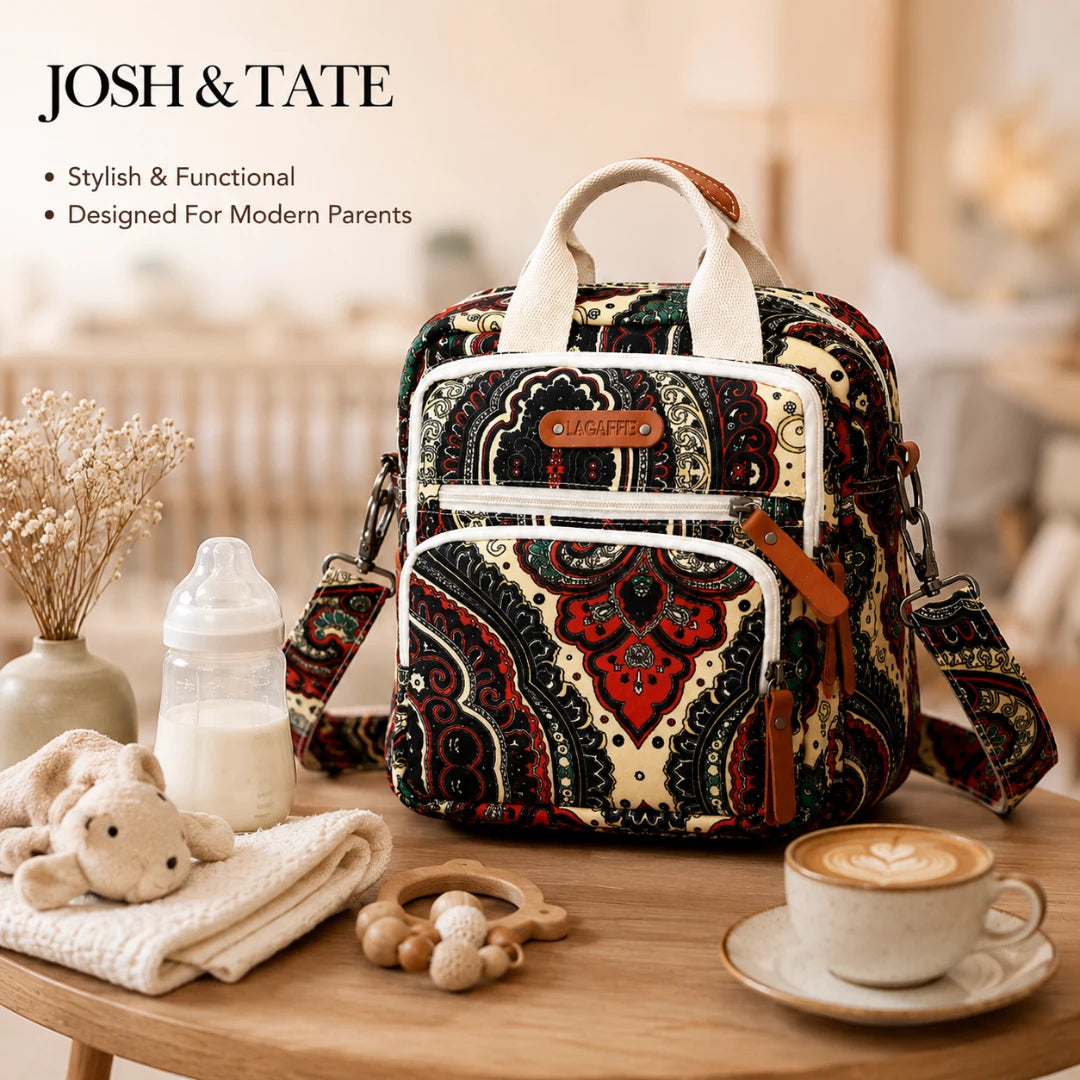 Josh & Tate - CarryAll™ Convertible Baby Bag - Patterned diaper bag on a table with baby items and a cup of coffee, featuring 'Josh & Tate' branding.