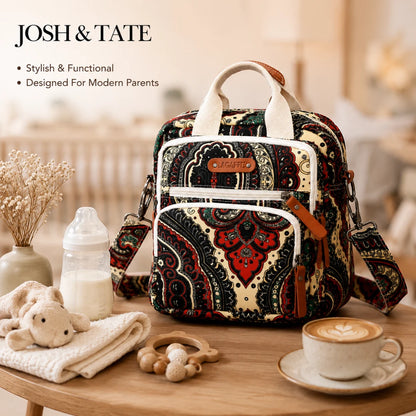 Josh & Tate - CarryAll™ Convertible Baby Bag - Patterned diaper bag on a table with baby items and a cup of coffee, featuring 'Josh & Tate' branding.