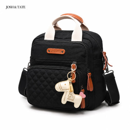 Josh & Tate - CarryAll™ Convertible Baby Bag - Black quilted backpack with brown accents and keychain on a white background, featuring the brand 'Josh & Tate'.