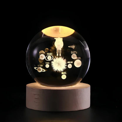 Decorative glass sphere with solar system design on a wooden base against a black background