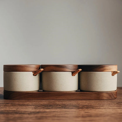 Josh & Tate - Ceramic Condiment Storage Set - Three ceramic containers with wooden lids and handles on a wooden stand against a neutral background