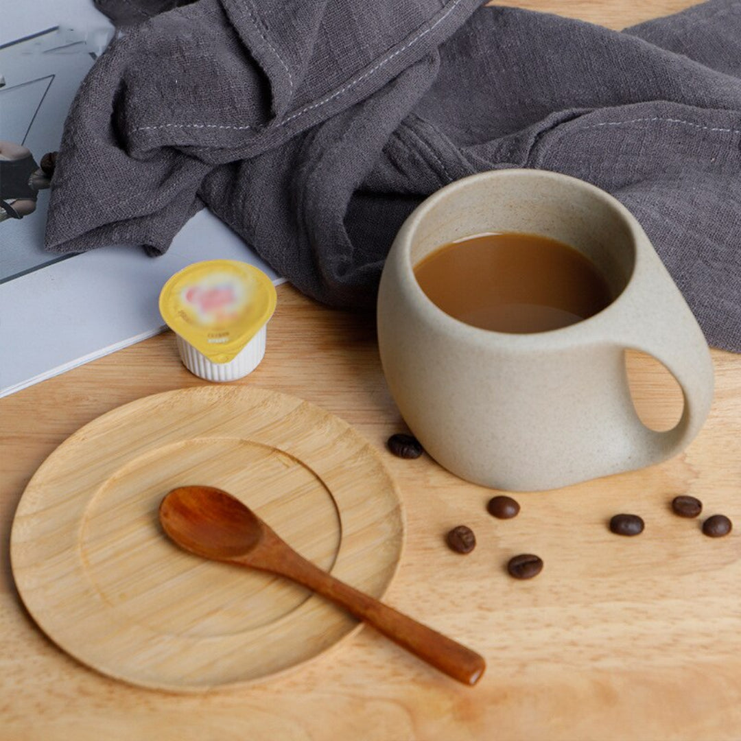 Cup of coffee on a wooden table with a wooden spoon and coffee beans.