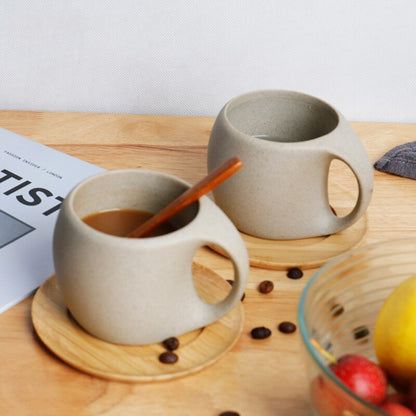 Two ceramic mugs on a wooden surface with coffee and cinnamon sticks, surrounded by coffee beans and fruits.