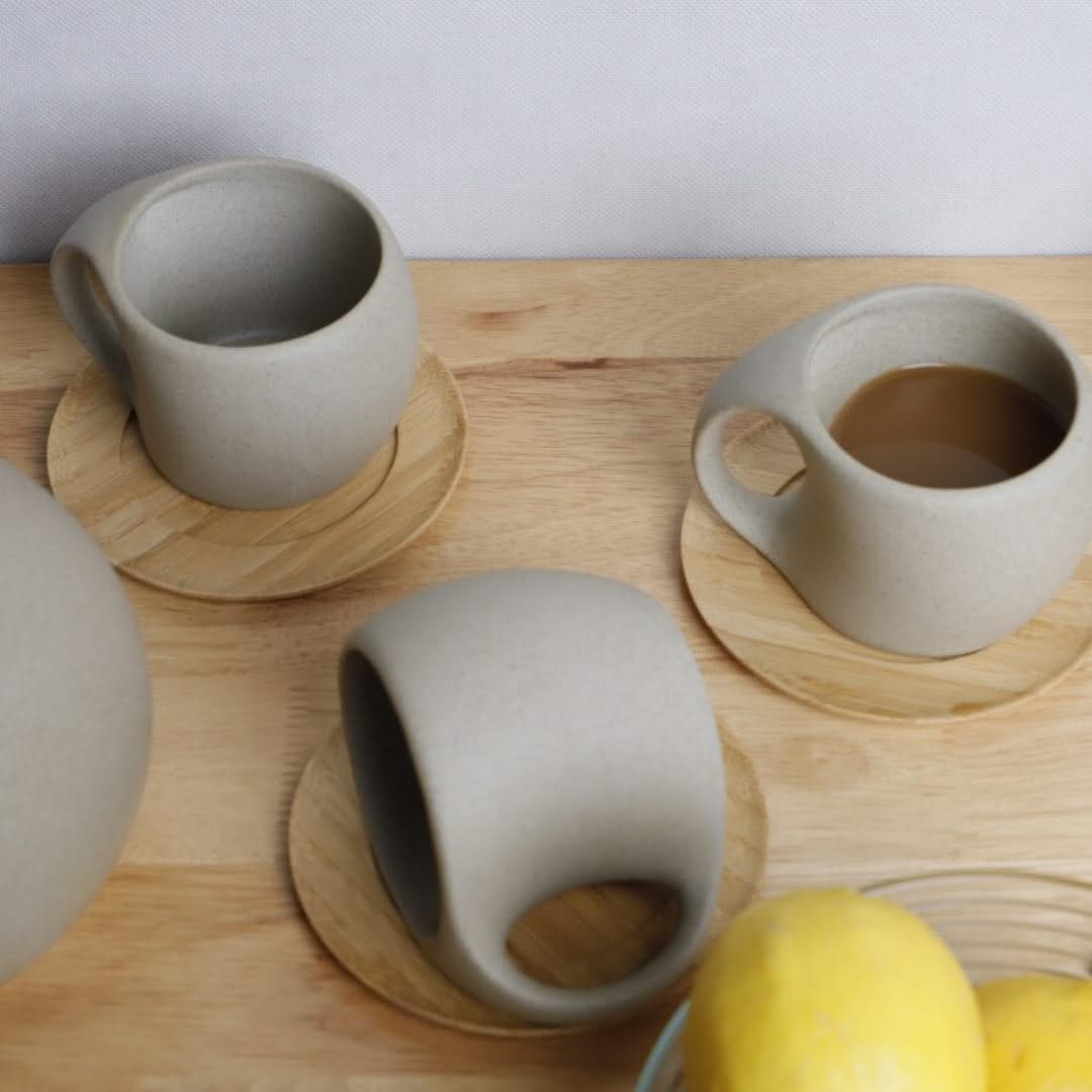 Three ceramic mugs on wooden coasters with a lemon on a wooden surface.