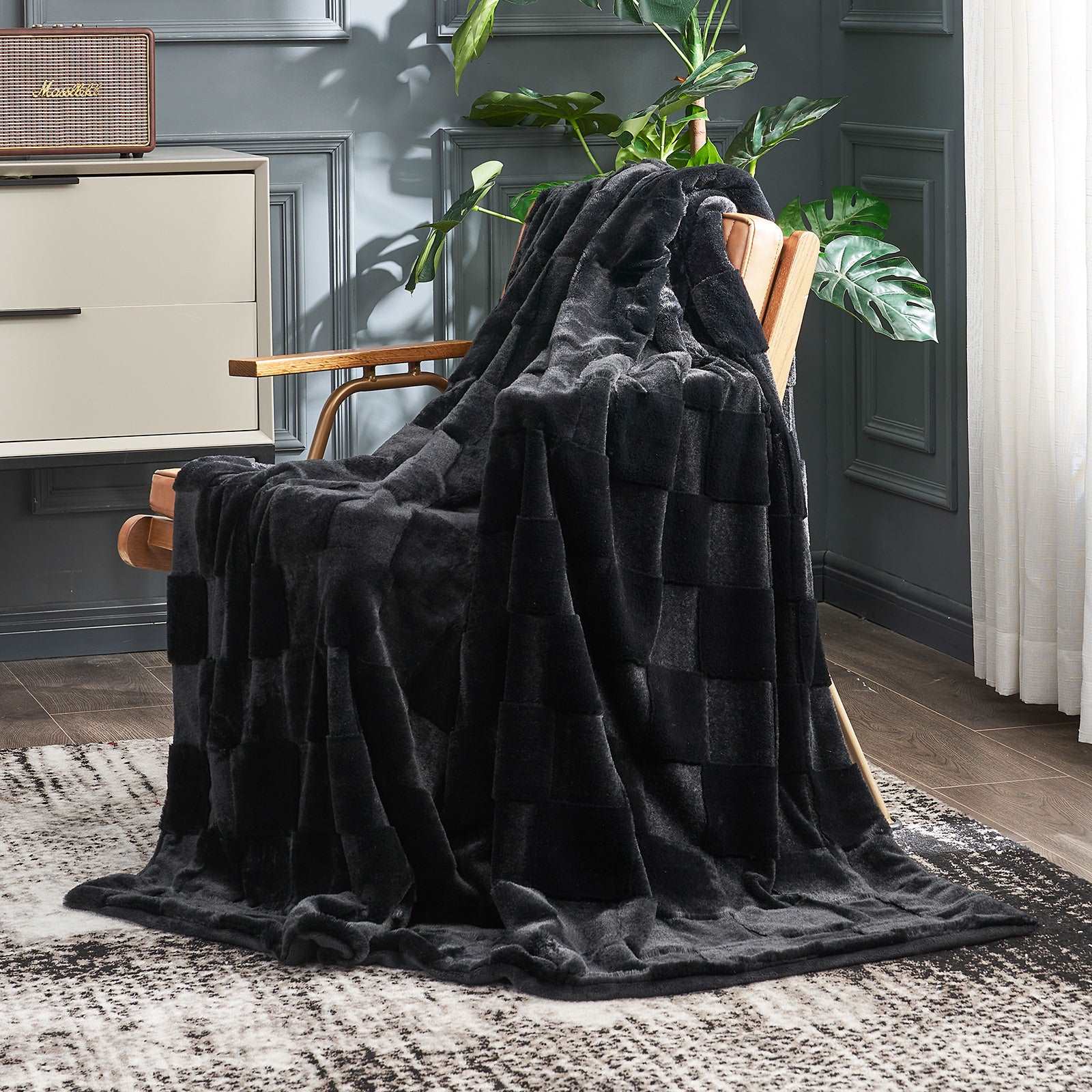 Dark gray blanket draped over a wooden chair in a room with a plant and cabinet.