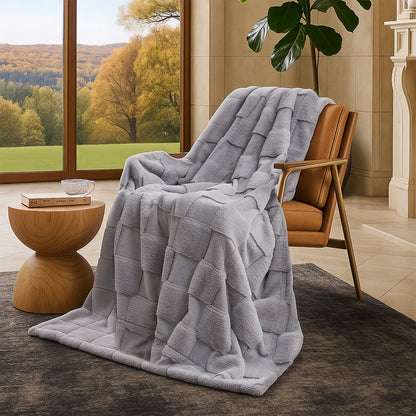 Gray textured blanket draped over a brown chair in a room with large windows showing a scenic view.