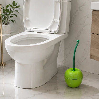 Josh & Tate - CherryPop™ Toilet Brush & Holder - A bright green apple-shaped toilet brush with a curved green handle resting beside a white ceramic toilet in a marble-look bathroom.