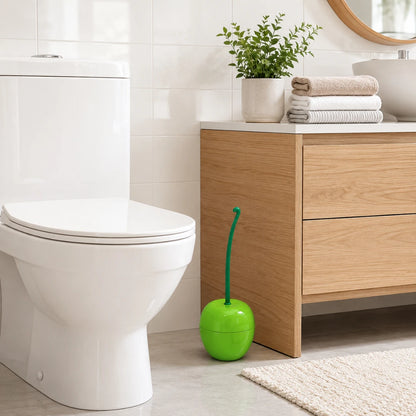 Josh & Tate - CherryPop™ Toilet Brush & Holder - A bright green apple-shaped toilet brush with a green handle sits on the floor next to a white toilet in a modern bathroom with light wood vanity and white tiles.