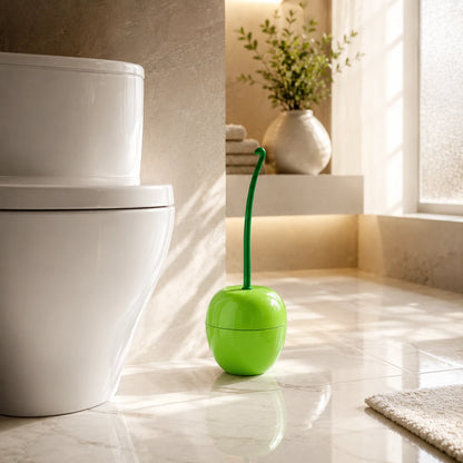 Josh & Tate - CherryPop™ Toilet Brush & Holder - A bright green toilet brush shaped like a cherry, with a long green stem handle, standing on a glossy tiled bathroom floor next to a white toilet.