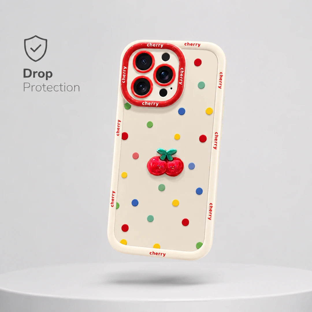 Josh & Tate - CherryPop™ iPhone Case - A cream-colored phone case with colorful cherry-themed polka dots and a 3D cherry accent on the back, shown floating above a white platform against a light gray background. The camera cutout has a red border with 'cherry' printed around it, and the word 'cherry' is repeated along the side border.