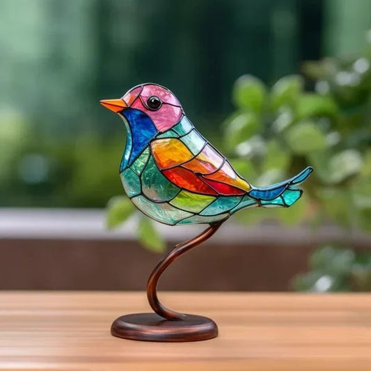 Colorful stained glass bird sculpture on a wooden surface with a blurred green background