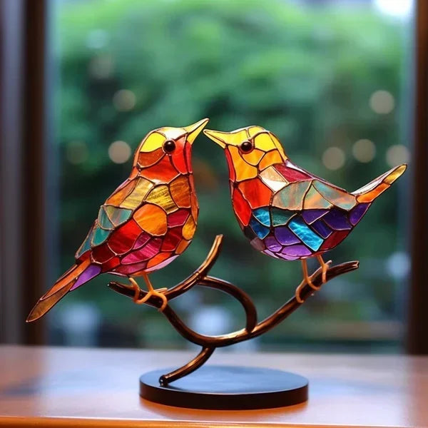 Colorful stained glass birds on a branch with a blurred green background