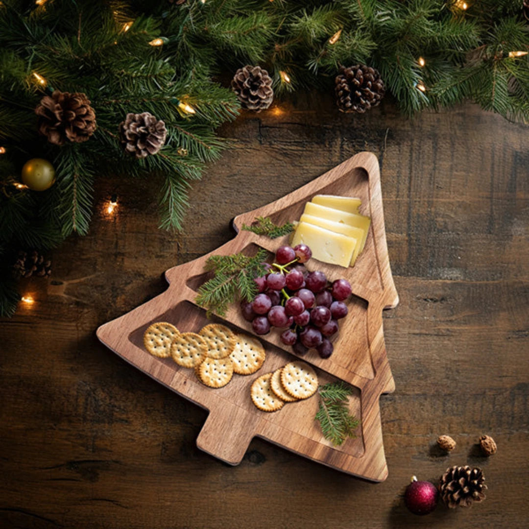 Josh & Tate - Christmas Tree Serving Board - Wooden Christmas tree-shaped cutting board with cheese, crackers, and grapes on a wooden surface with a festive background.
